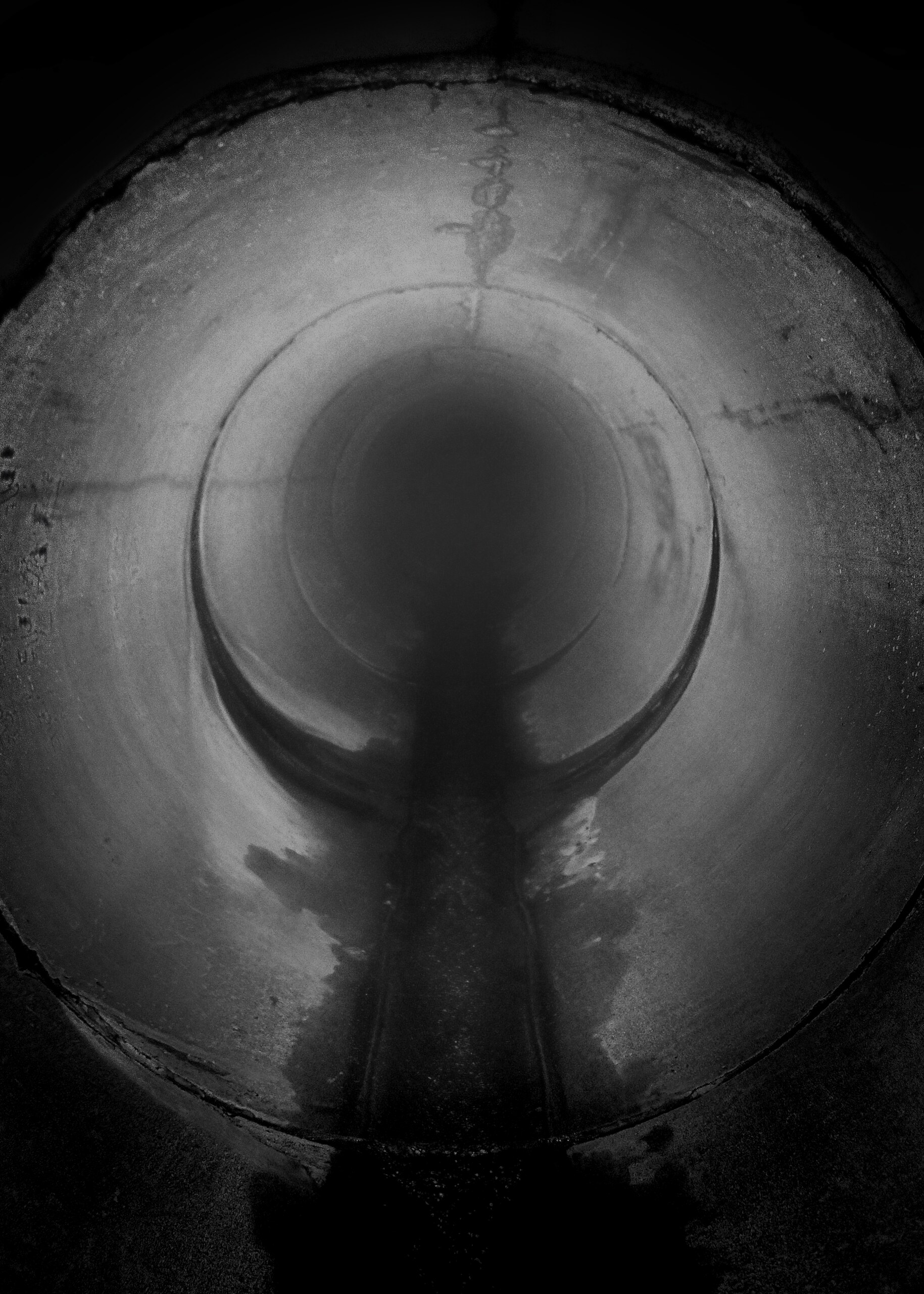 A round tunnel receding into darkness toward a pale light.