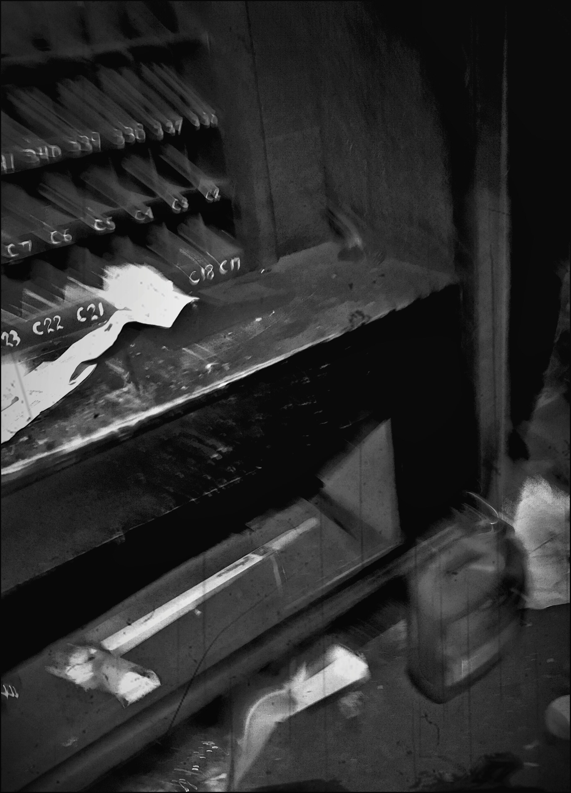 An old keyboard instrument with missing keys, in heavy shadow.