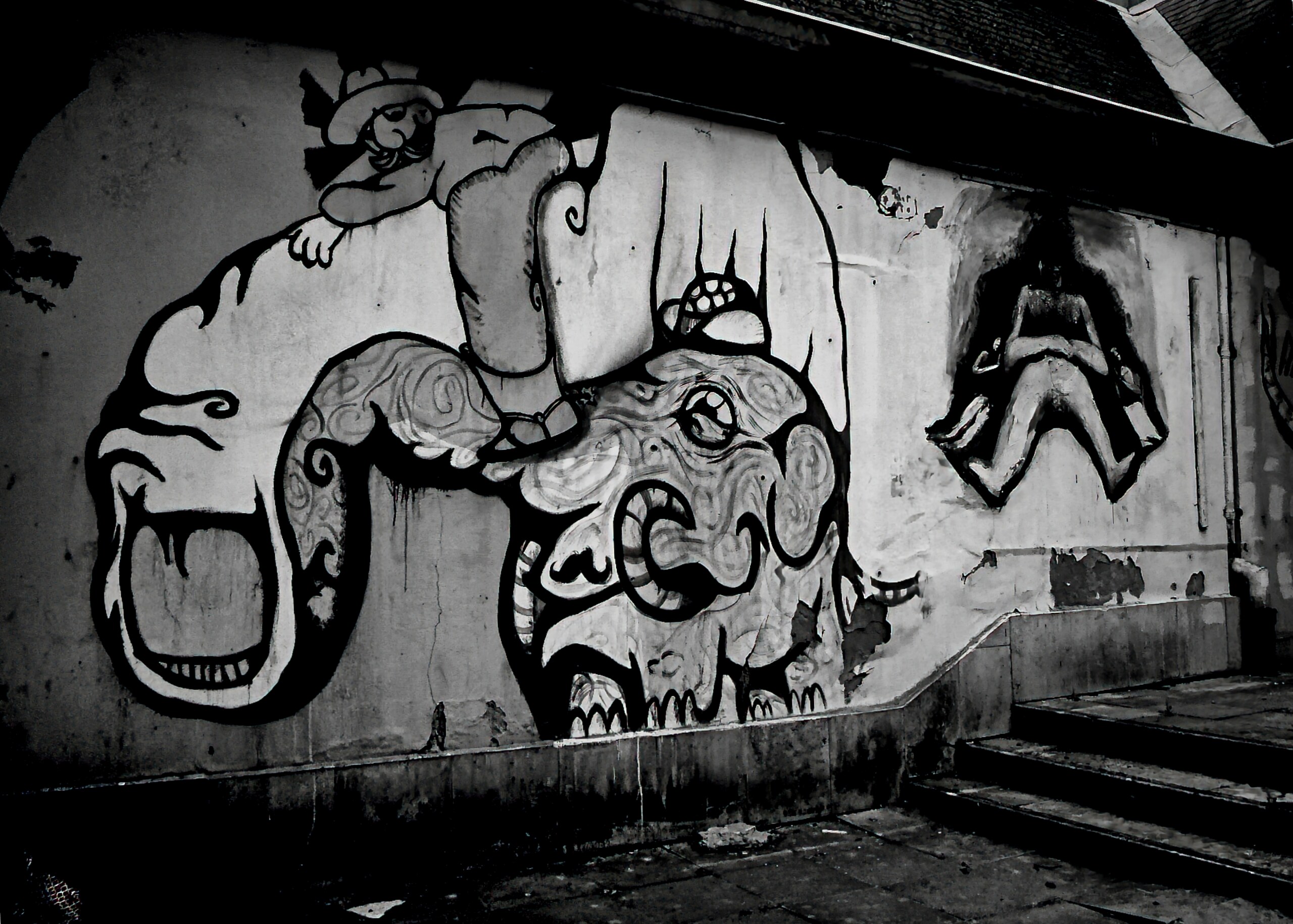 Graffiti of strange creatures painted across a curved wall.