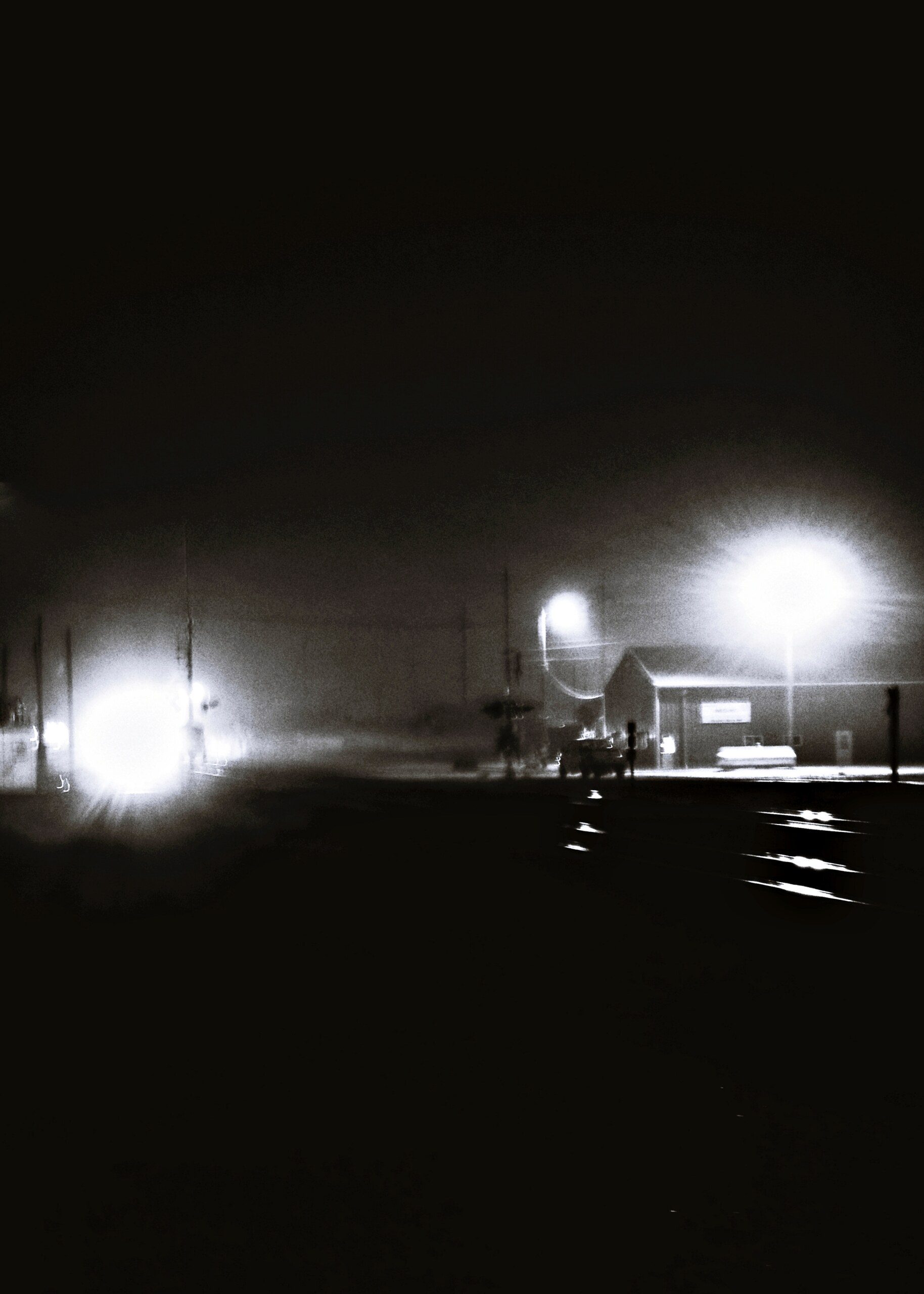 Two lights glowing through darkness and fog at night.